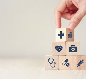 Das Bild zeigt sechs Holzwürfel mit Symbolen aus der Medizin