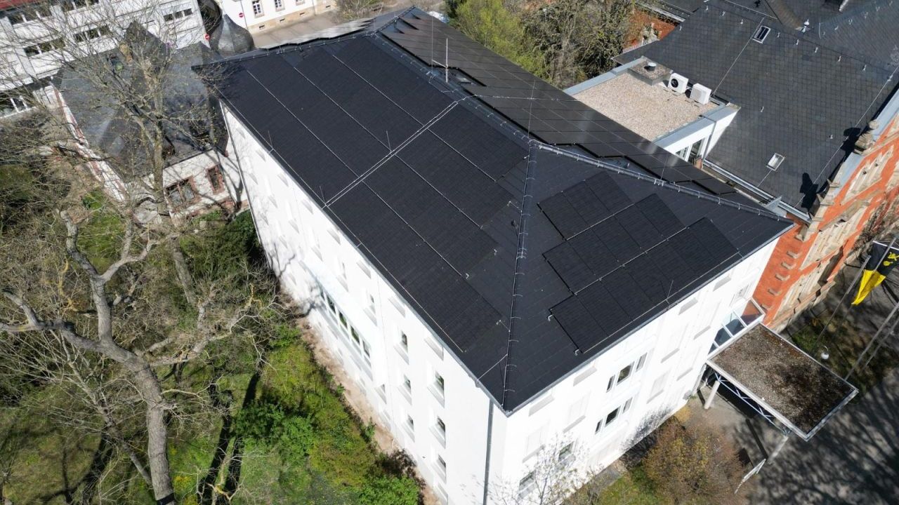 Das Bild zeigt ein Rathaus mit PV-Anlage von oben