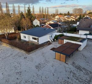 Das Bild zeigt eine Müllleinhausung mit Dachbegrünung auf einem Schulhof