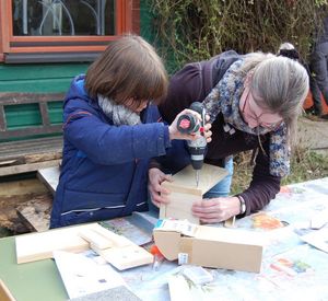 Das Foto zeigt ein Kind mit Erwachsenem beim Nistkastenbau