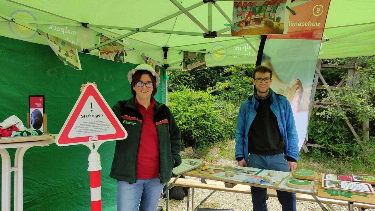 Das Bild zeigt zwei Personen in einem grünen Pavillion